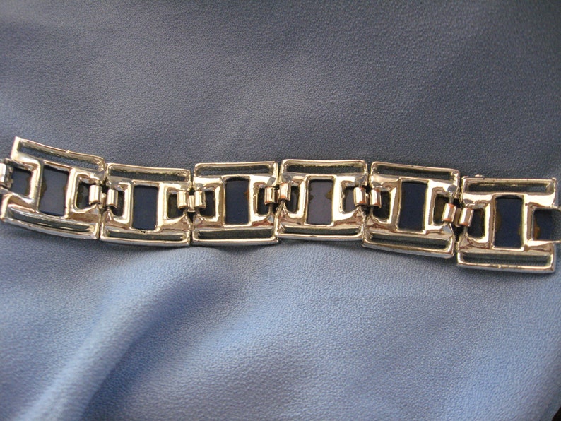May include: A silver bracelet with a chain link design and dark blue enamel accents.
