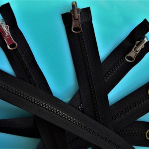 Peut inclure: Cinq fermetures éclair noires avec des tirettes métalliques de différentes couleurs. Les fermetures éclair sont disposées en étoile sur un fond bleu.