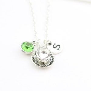 Peut inclure: Collier en argent avec un pendentif en forme de tasse à thé, un pendentif en cristal vert et un pendentif en argent avec la lettre 'S'.