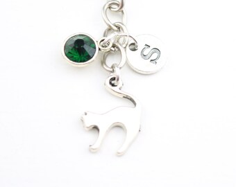 May include: Silver keychain with a green crystal charm, a silver charm with the letter "S" and a silver cat charm.