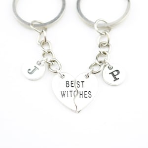 May include: Two silver keychains with a broken heart charm that says "Best Witches" and initial charms that say "J" and "P".