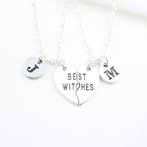 Puede incluir: Dos collares de plata con dijes a juego. Un dije es un corazón que dice "Best Witches" y está roto por la mitad. Los otros dos dijes son redondos y tienen las letras "J" y "M" en ellos.