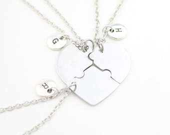 May include: Three silver necklaces with heart-shaped puzzle pieces and small round charms with the letters F, G, and H.