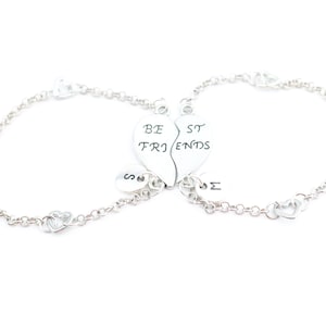 May include: Two silver bracelets with heart charms that say "Best Friends" on them. The hearts are broken in half and fit together.