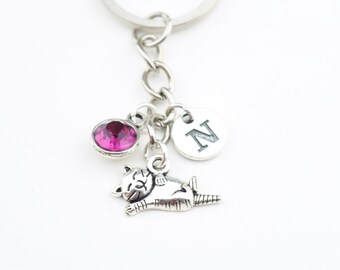 May include: Silver keychain with a pink crystal charm, a silver charm with the letter N, and a silver charm of a cat.