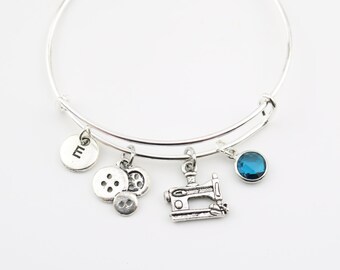 Bedelarmband naaister: naaimachine, knoop, initiaal en kristal