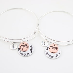 May include: Two silver charm bracelets with a pink promise ring charm and the words "no matter what" on each charm. The charms are attached to the bracelets with a silver ring.