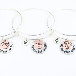 May include: Three silver charm bracelets with different charms. The first charm says "no matter what" and has a pinkie promise symbol. The second charm says "no matter where" and has a compass. The third charm says "no matter when" and has a sun and moon.