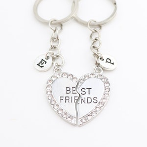 May include: Two silver keychains with a broken heart charm that says "BEST FRIENDS" and two small silver charms with the letters "E" and "P" on them.