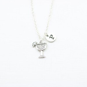 May include: Silver necklace with a charm of a margarita glass and a silver disc with the letter "P" on it.