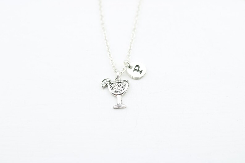 May include: Silver necklace with a charm of a margarita glass and a silver disc with the letter "P" on it.