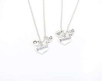 Peut inclure: Deux colliers en argent avec des pendentifs en forme de cœur qui disent "Bridesmaid" et l'année "2022". Chaque collier a également un charme avec une lettre, "C" et "B".