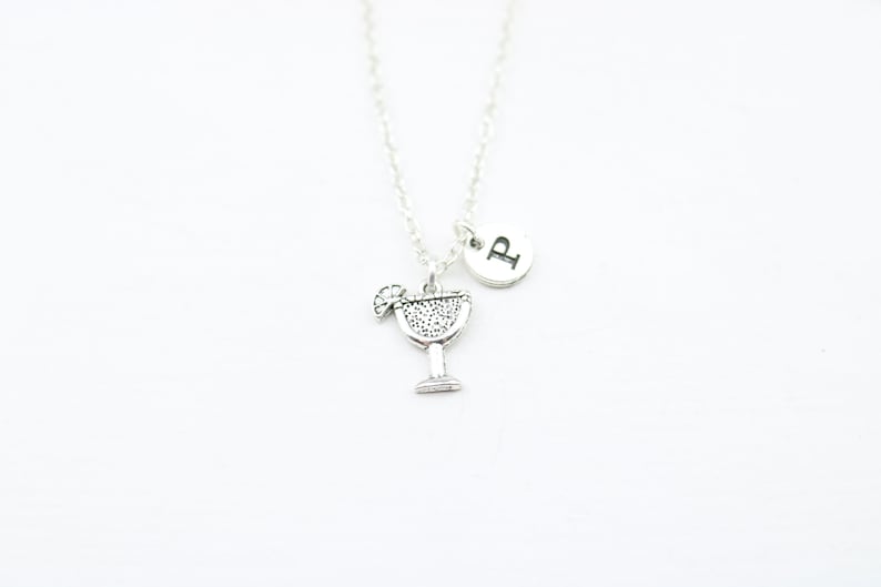 May include: Silver necklace with a charm of a margarita glass and a small round charm with the letter "P" on it.