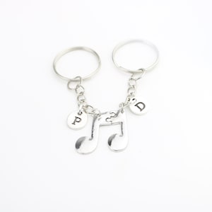 Puede incluir: Dos llaveros plateados con dos dijes de notas musicales y dijes de letras que dicen "P" y "D".