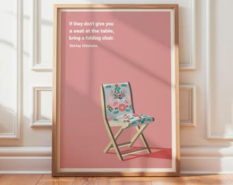 May include: A framed print featuring a pink background and a folding chair with a floral pattern. The text reads: "If they don't give you a seat at the table, bring a folding chair. Shirley Chisholm." The frame is wood-toned. "Frame not included" is at the bottom.