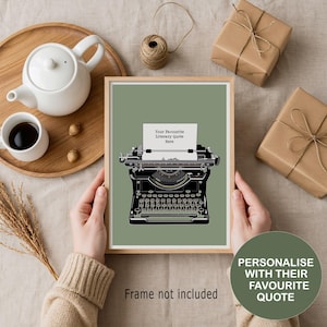 May include: A framed print of a vintage black typewriter with the text "Your Favourite Literary Quote Here" on a pale green background. The print is held by hands, with a wooden tray, teapot, and wrapped gifts in the background. The text "Frame not included" is also visible.