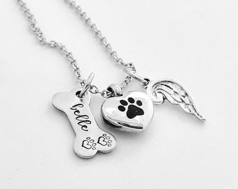 Puede incluir: Un collar plateado con tres colgantes: un hueso con el nombre "Belle", un corazón con una huella de pata y un ala. El colgante de hueso tiene dos huellas de pata. Los colgantes de corazón y ala están conectados a la cadena.