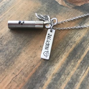 May include: Silver necklace with a small urn, a paw print charm, and a tag that says "JACKSON" with a paw print heart.