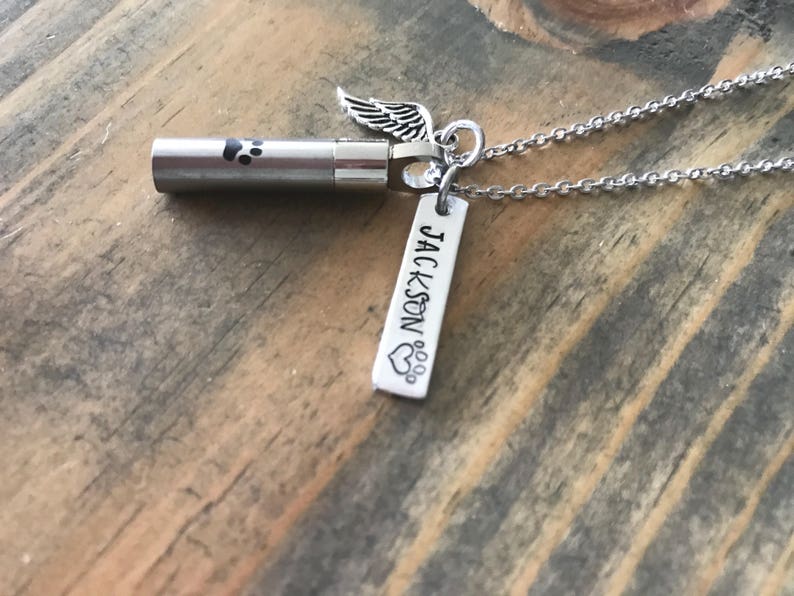 May include: Silver necklace with a small urn, a paw print charm, and a tag that says "JACKSON" with a paw print heart.