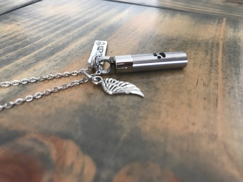 May include: Silver necklace with a small silver urn pendant, a silver wing charm, and a tag that reads "Always in my heart".