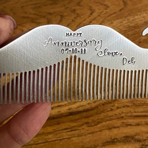 Puede incluir: Un peine de plata en forma de bigote con una inscripci&oacute;n personalizada que dice "Happy Anniversary 07.10.11 Love, Del."