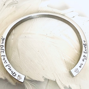 May include: Silver bangle bracelet with the inscription "You left paw prints on my heart" and a paw print symbol.