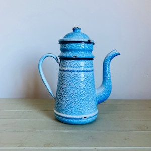 May include: A blue enamel coffee pot with a textured finish and a lid. The pot has a spout and a handle.