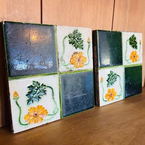 Può includere: Due set di quattro piastrelle quadrate in ceramica. Ogni piastrella ha uno sfondo bianco con un bordo verde e un quadrato verde scuro. Le piastrelle presentano un motivo floreale giallo e foglia verde.