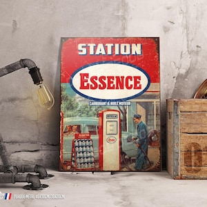 Può includere: Un cartello in metallo in stile vintage con colori rosso, bianco e blu. Il cartello recita "Station Essence" e "Carburant & Huile Moteur". Presenta una pompa di benzina e un'auto con una persona che fa rifornimento.