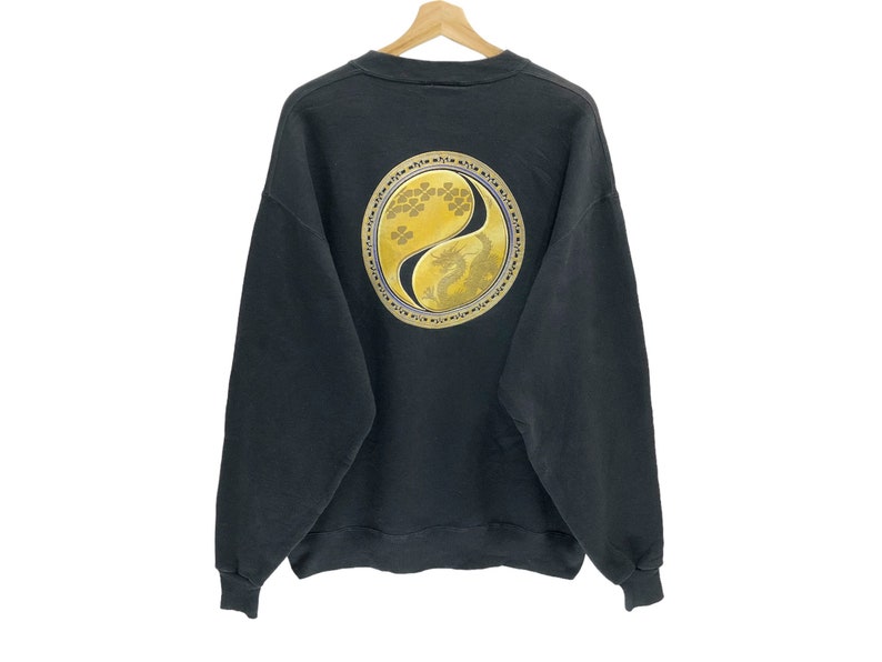 Puede incluir: Sudadera negra con un s&iacute;mbolo yin yang dorado con un dise&ntilde;o de drag&oacute;n en la espalda.