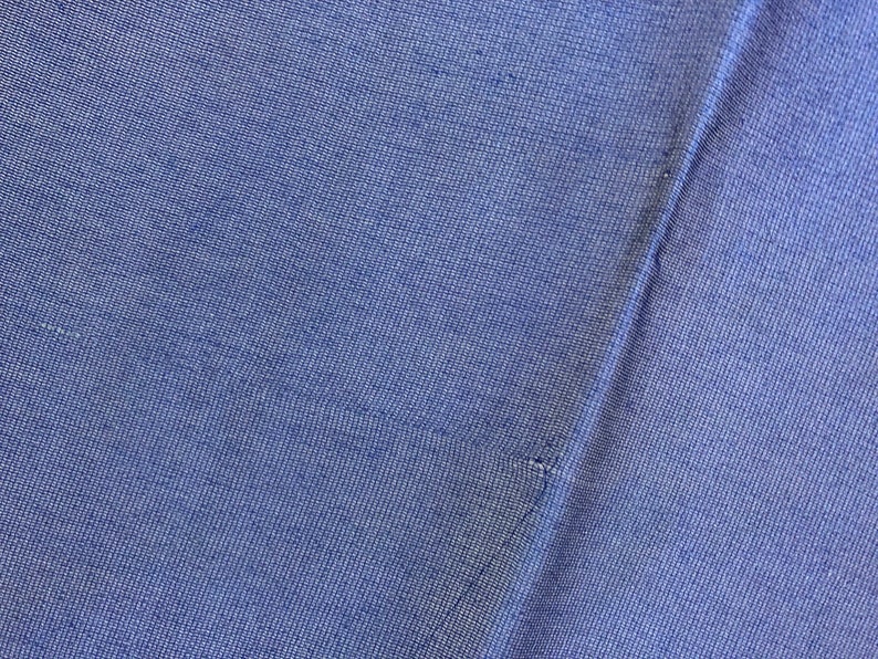 May include: Close-up of a blue fabric with a textured weave. The fabric is folded in half, creating a seam down the center.