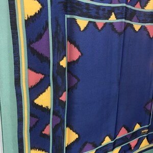 May include: A blue silk scarf with a geometric pattern in shades of yellow, pink, purple, and black. The scarf has a green border and a small label that reads "MISSONI ITALY".