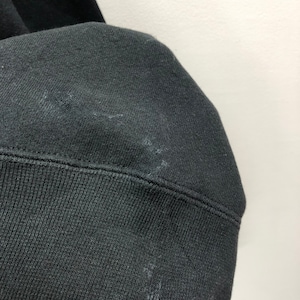 Puede incluir: Primer plano del pu&ntilde;o de tela negra de una sudadera. La tela es suave y texturizada.