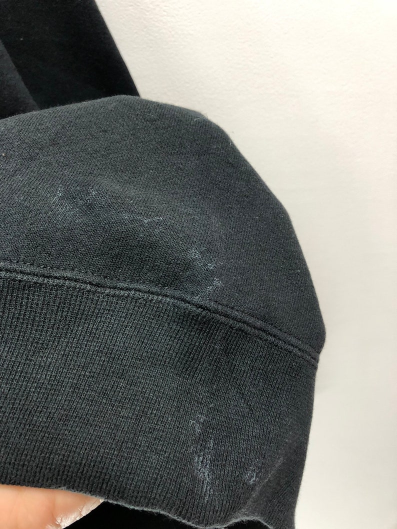 Puede incluir: Primer plano del pu&ntilde;o de tela negra de una sudadera. La tela es suave y texturizada.