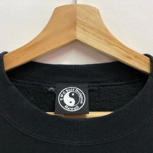 Puede incluir: Sudadera negra con un logotipo redondo de yin yang blanco y negro que dice "T.Y.C. Surf Designs Hawaii".