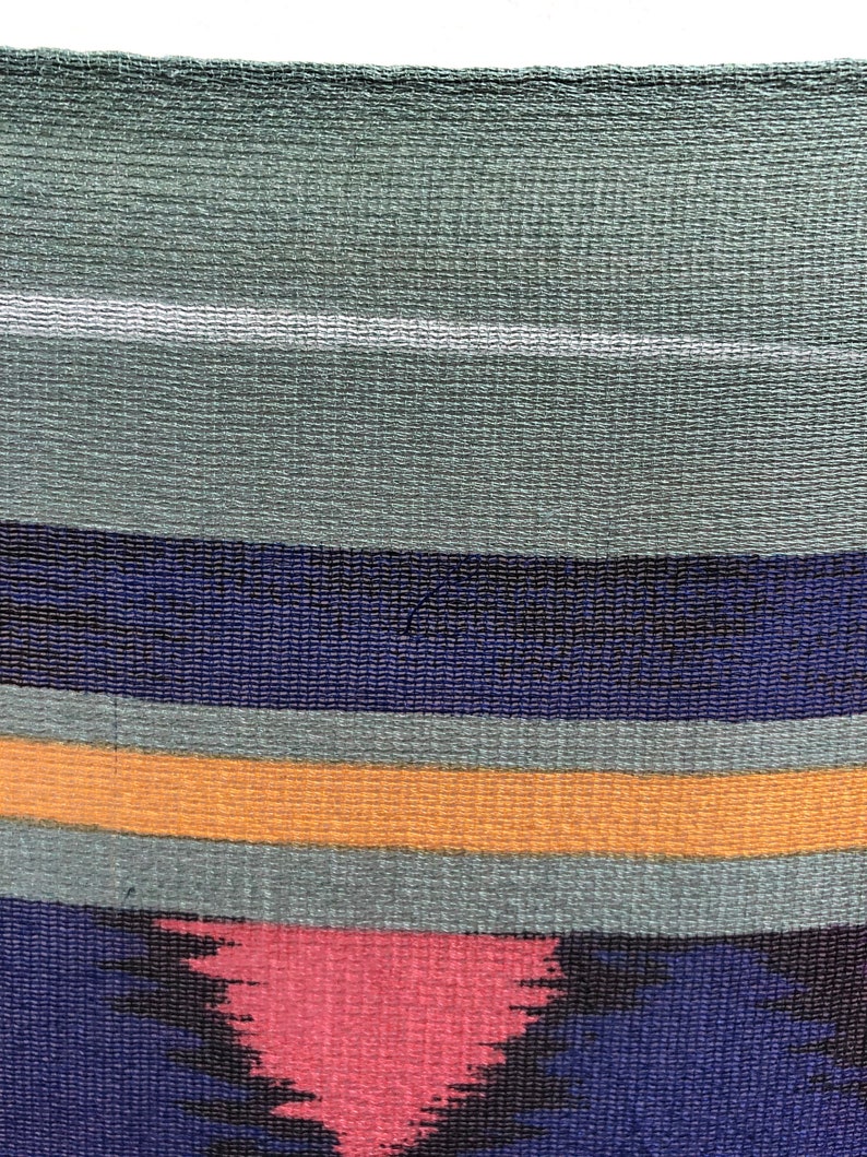 May include: A woven tapestry with a geometric pattern in shades of blue, green, orange, and pink.