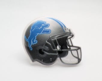 May include: A white and gray football helmet with a blue lion logo. The helmet has a clear face mask.