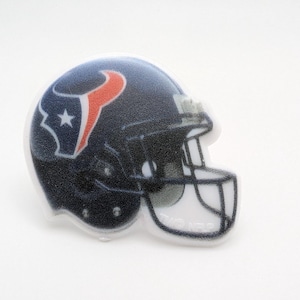 May include: A white football helmet with a blue and red Houston Texans logo. The helmet is a 3D printed design.