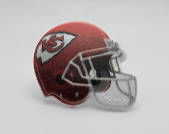 May include: A red, white, and gray plastic football helmet with the Kansas City Chiefs logo. The helmet has a clear face mask and the text "TMG NFL" is printed on the side.