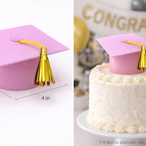 May include: A pink graduation cap cake topper with a gold tassel. The cap measures 4 inches wide, 3.95 inches long, and 2.7 inches high. The cake topper is placed on top of a white frosted cake. Graduation party decorations.