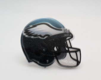 May include: A black and white football helmet with a blue and white eagle design. The helmet has a clear plastic face mask and the text "TWO-FER" printed on the side.