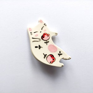 Small ceramic cat brooch with pink and red floral decoration, modeled and decorated by hand