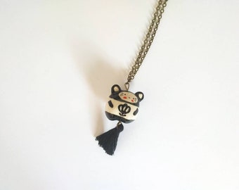 Collier sautoir avec pendentif "chat" en faïence blanche modelé et décoré à la main, avec décor de fleur noire et pompon noir