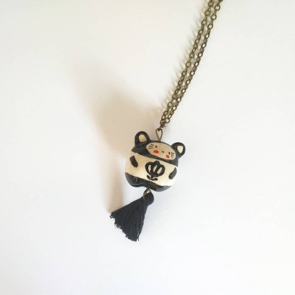 Collier sautoir avec pendentif "chat" en faïence blanche modelé et décoré à la main, avec décor de fleur noire et pompon noir