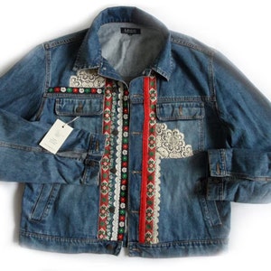 Könnte beinhalten: Eine blaue Jeansjacke mit roten, weißen und grünen Stickereien und Spitzendetails.