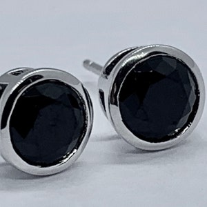 May include: A pair of silver stud earrings with black round gemstones.