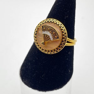 Op de afbeelding: Gouden ring met een ronde, crèmekleurige cabochon met een zwart-witte waaierontwerp.