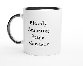 May include: White ceramic mug with a black rim and handle. The mug features the text "Bloody Amazing Stage Manager" in black, centered on the front. The mug is set against a white background.