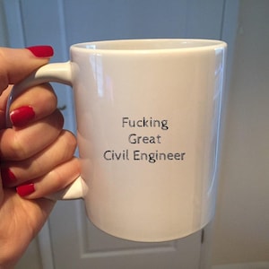 Puede incluir: Taza de cerámica blanca con el texto "Fucking Great Civil Engineer" en negro. La taza está sujeta por una mano con esmalte de uñas rojo.