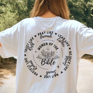 May include: White t-shirt with a black circle design featuring the text "Women of the Bible" and a Bible with flowers. The circle also includes phrases like "Trust like Ruth", "Pray like Hannah", "Lead like Esther", "Rejoice like Mary", "Protect like Sarah", and "Wait like  Song of Songs".